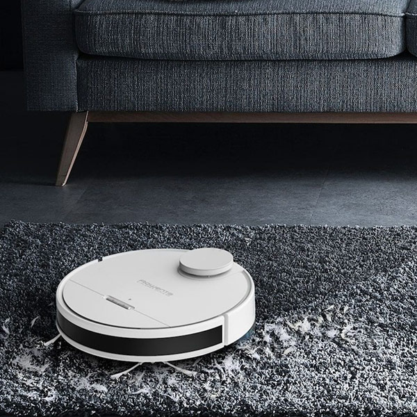 Un aspirateur robot qui aspire un tapis gris dans un salon