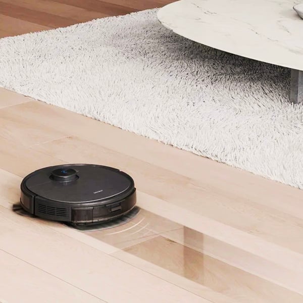 Un aspirateur robot dans un salon avec un tapis et une table basse