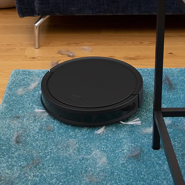 Un aspirateur robot qui aspire un tapis bleu