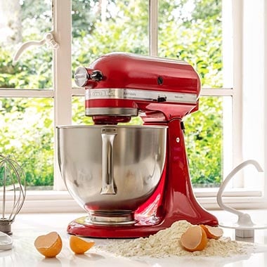 Un robot ptissier rouge KitchenAid, des oeufs et de la farine dans une cuisine