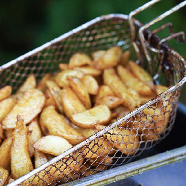 Versgebakken aardappelpartjes in een friteusemand