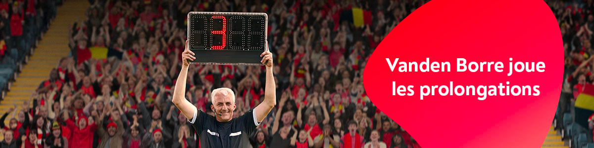  Un arbitre dans le stade tenant un panneau de changement, avec des supporters enjous derrire lui.