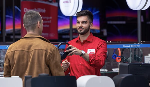 Een Vanden Borre-medewerker in de afdeling Audio geeft een hoofdtelefoon aan een klant. 