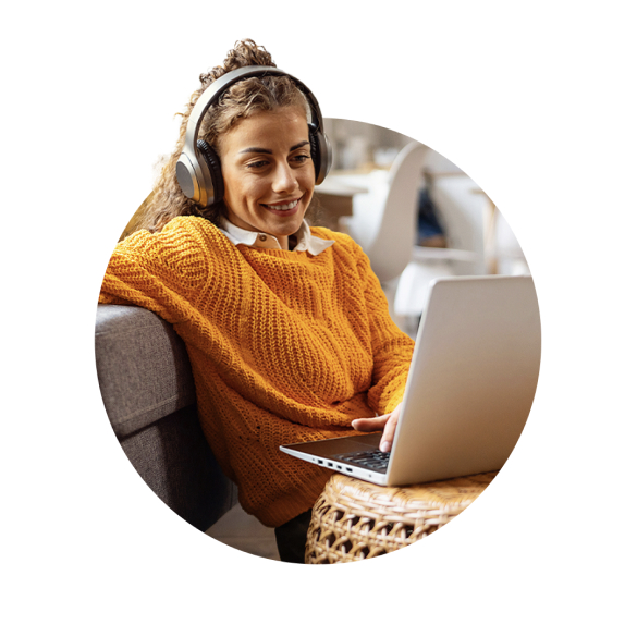 Une femme avec un casque audio qui regarde l'cran de son PC portable en souriant