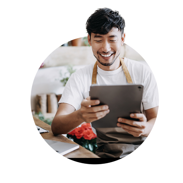 Un homme cuisine et sourit en regardant l'cran de sa tablette