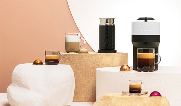 Een witte Nespresso koffiemachine met drie soorten koffie