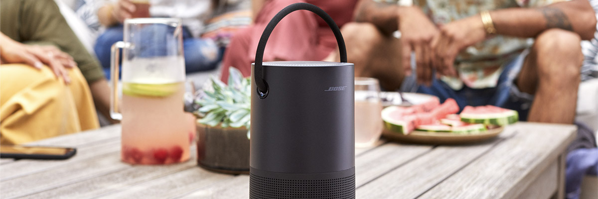 Une enceinte Bluetooth Bose pose sur une table avec des gens autour  