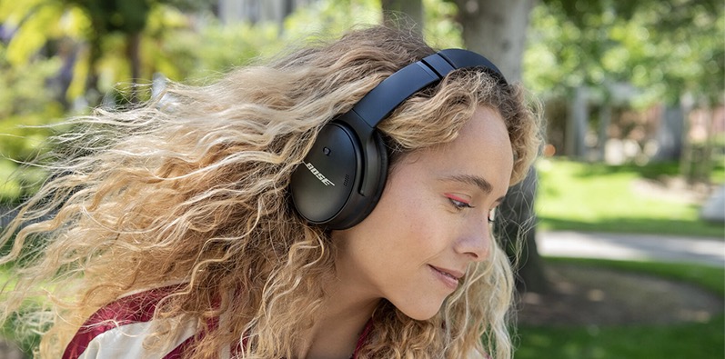 Une femme qui porte son casque Bose QuietComfort 45  l'extrieur 