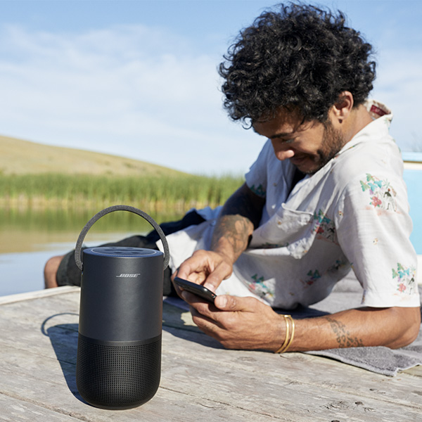 Un homme avec son enceinte Bluetooth Bose Portable Home Speaker au bord dun lac  