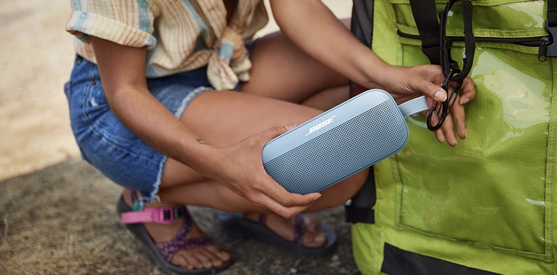 Une femme qui accroche son enceinte Bluetooth Bose SoundLink Flex  son sac  