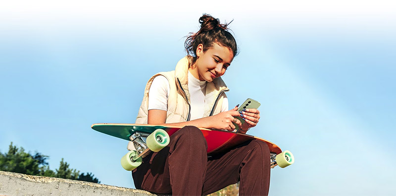 Une femme avec son skateboard qui utilise son smartphone A