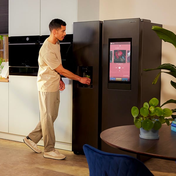 Un homme qui utilise la fontaine de son frigo amricain noir dans sa cuisine 