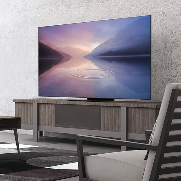 Une TV QLED Samsung dont le fond dcran prsente des fjords, pose sur un meuble TV dans un salon 