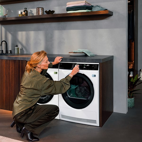 Un femme qui choisit le programme du sche-linge